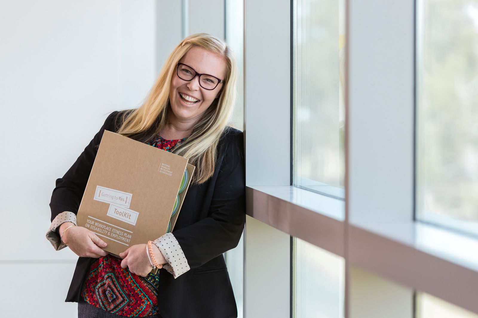 woman smiling and holding a work folder