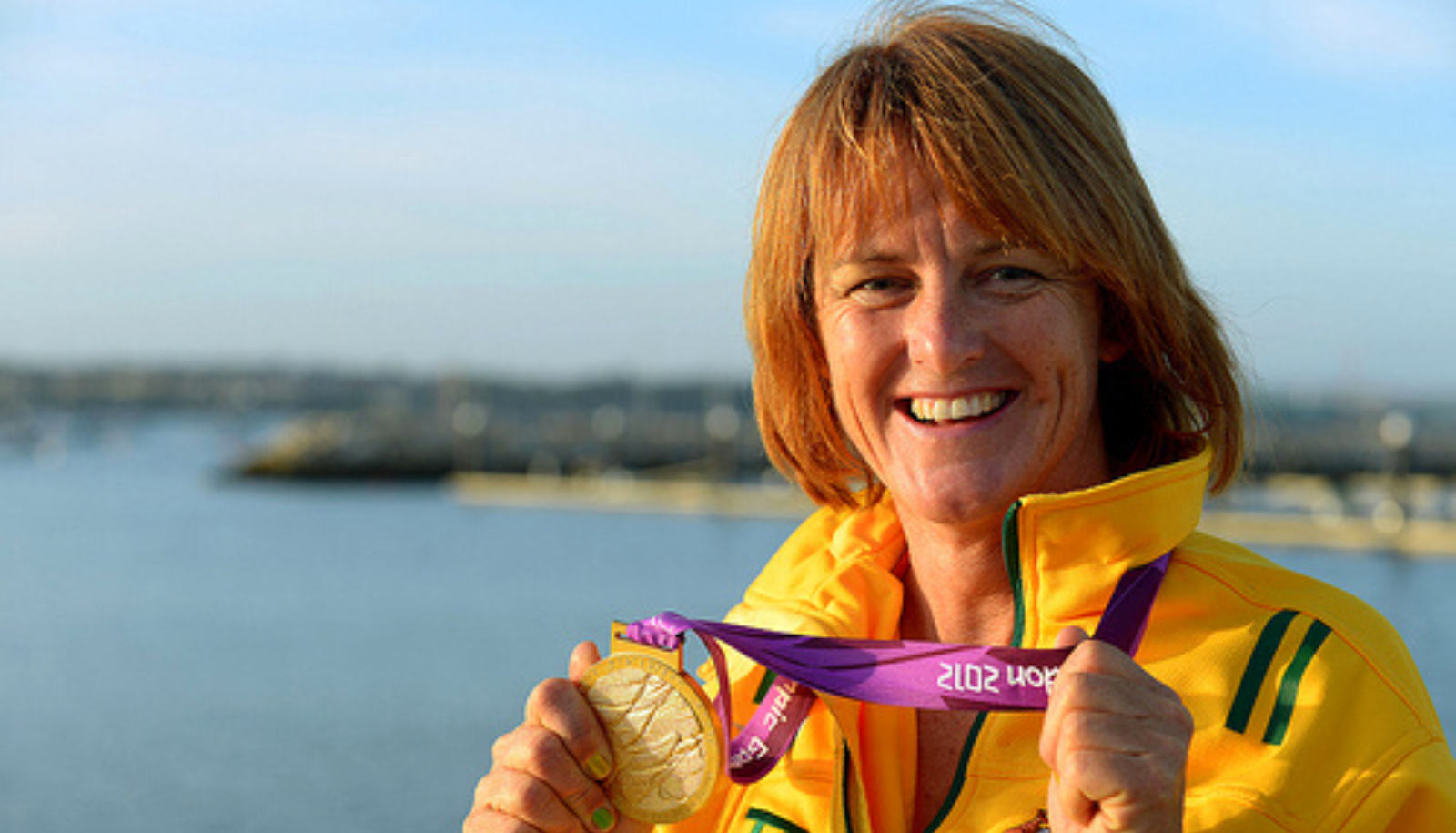 : Liesl Tesch wearing Australian team colors and holding a gold medal at the London 2012 Paralympic Games.