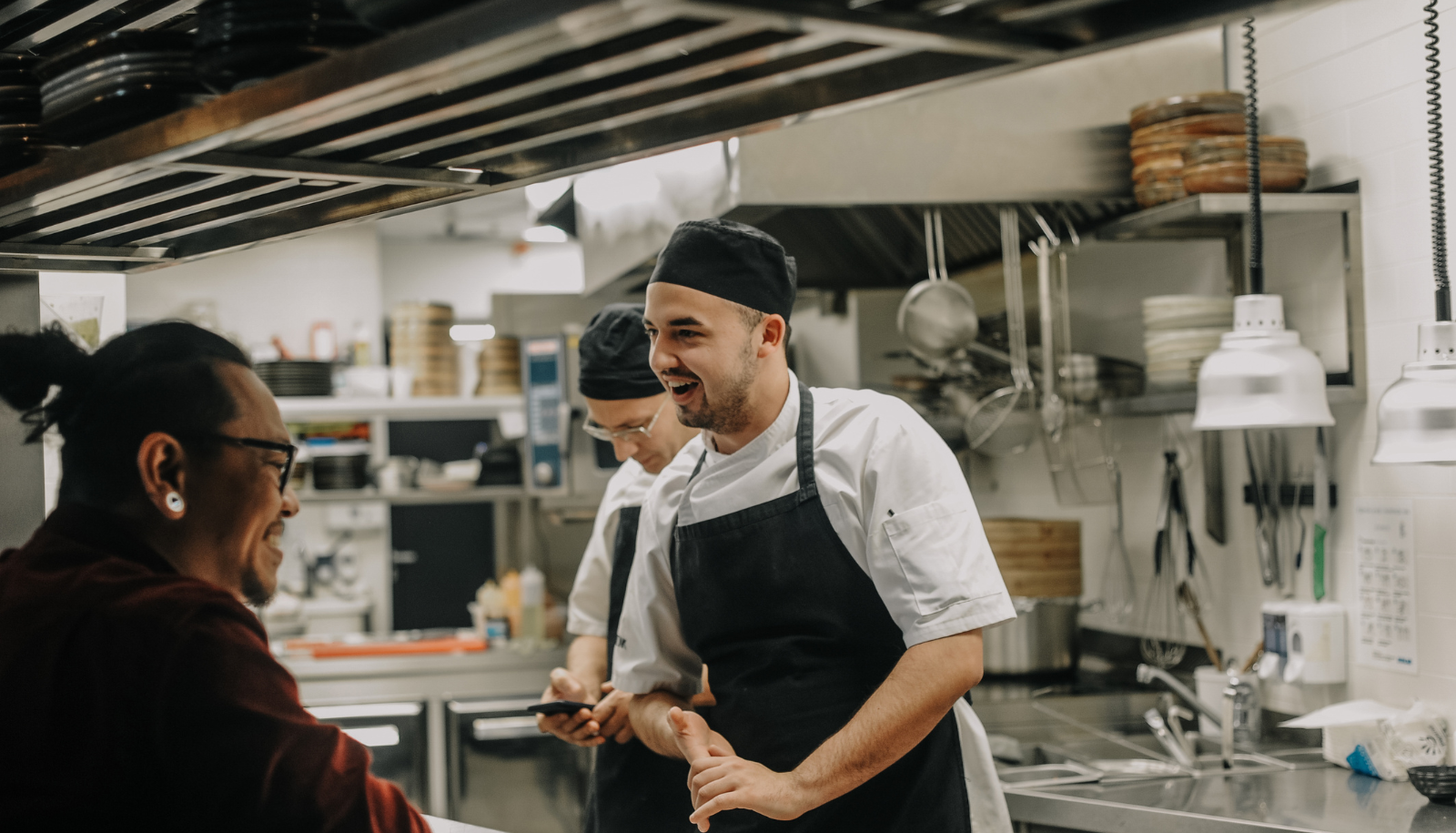 a man in a restaurant kitchen having a conversation with a customer