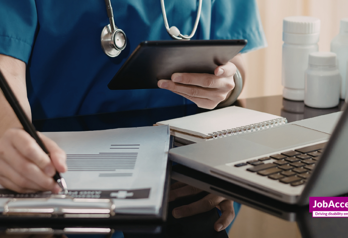 Image of a person hand writing on a pd with a opened laptop in front of them